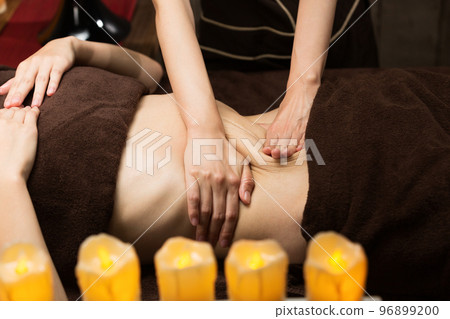 A woman is getting an oil massage on her tummy. 96899200