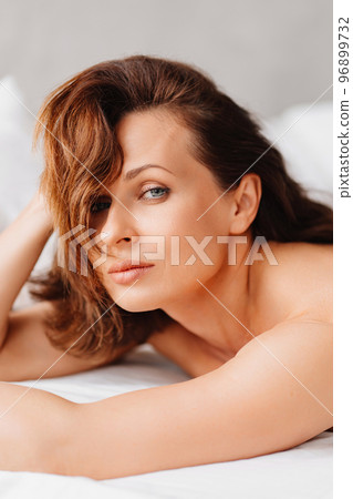 sexy naked brunette woman lying in bed. women's health and attractiveness. 96899732