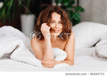 sexy naked brunette woman lying in bed. women's health and attractiveness. 96899733