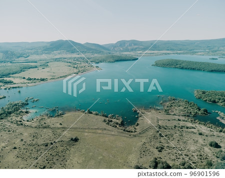 Aerial view on mountain lake. Drone over water reservoir at mountain valley covered with green spring forest. Beautiful view from above on smooth blue surface of mountain lake among highlands. Nobody Aerial view on mountain lake. Drone over water reservoir at mountain valley covered with green spring forest. Beautiful view from above on smooth blue surface of mountain lake among highlands. Nobody 96901596