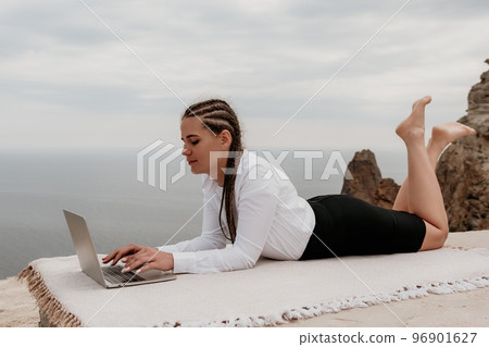 Silhouette of laptop and cup on the beach over sea sunset. Sparkling sea water on background. Freelancer, blogger working on notebook on the beach. Silhouette of laptop and cup on the beach over sea sunset. Sparkling sea water on background. Freelancer, blogger working on notebook on the beach. 96901627