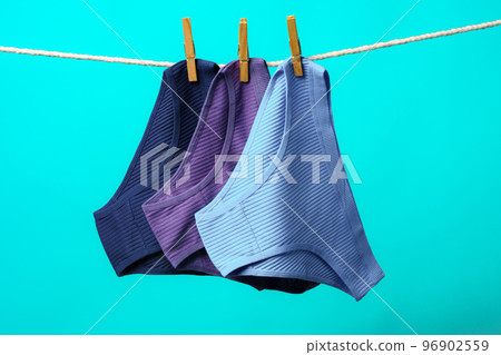 Female panties hanging on rope against blue studio background Female panties hanging on rope against blue studio background 96902559