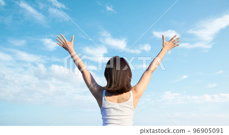 Asian woman holding her hands up against the blue sky 96905091