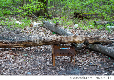 A rusted disposable barbecue grill thrown near a fire A rusted disposable barbecue grill thrown near a fire 96906017