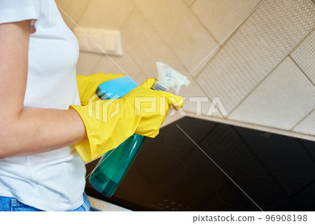 Woman in rubber gloves cleaning induction stove 96908198
