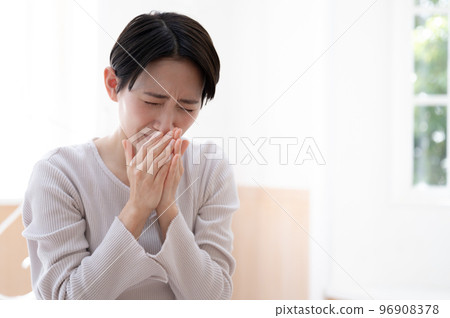 A woman who is sneezing and has a cold A woman who is sneezing and has a cold 96908378