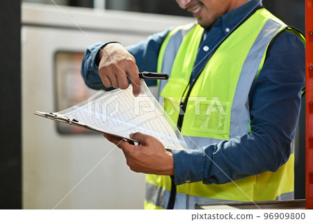 Male warehouse manager holding clipboard checking quantity of storage product in a large warehouse 96909800