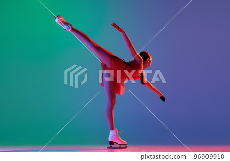 Young sportive girl, junior female figure skater in red stage costume skating isolated over gradient green-blue background in neon light. Grace, beauty, winter sports 96909910