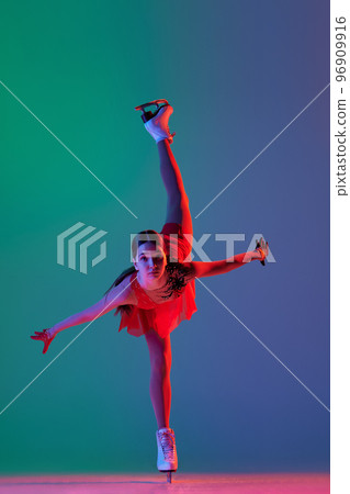 Young sportive girl, junior female figure skater in red stage costume skating isolated over gradient green-blue background in neon light. Grace, beauty, winter sports 96909916