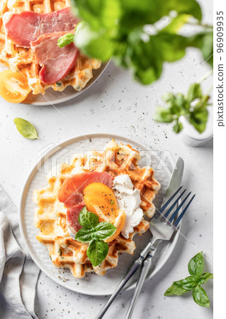 Cheese or potato savory waffles served with with tomatoes, cream cheese, ham and bazil leaves with cutlery. Delisious savory breakfast. Top view, flat lay 96909935