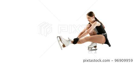 Studio shot of beautiful female figure skater in black festive stage dress practicing base elements of short program. Winter sports, flexibility, beauty 96909959