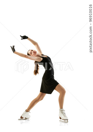Portrait of flexible young girl, female figure skater in black stage costume skating isolated over white background. Junior athlete in motion. Sport, beauty, winter sports 96910016