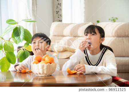 亞洲孩子在客廳的被爐上吃橘子 96911525