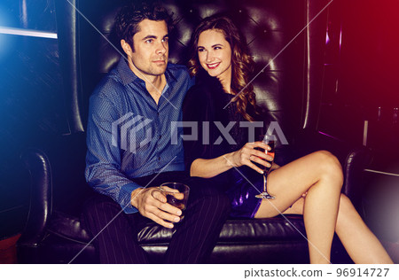 Party, club and couple sitting on a sofa together in a nightclub for a new year celebration or event. Music, birthday and disco with a man and woman bonding while clubbing in a luxury venue 96914727