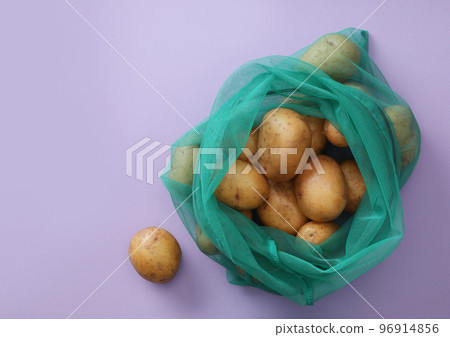 Net bag with potatoes on lilac background, top view 96914856