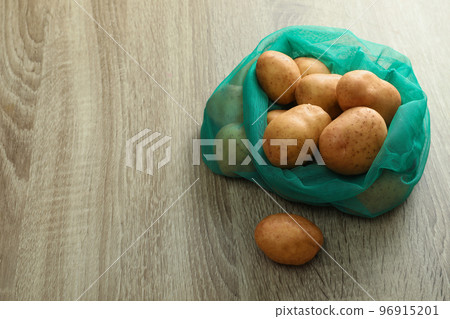Net bag with potatoes on wooden table. Space for text Net bag with potatoes on wooden table. Space for text 96915201