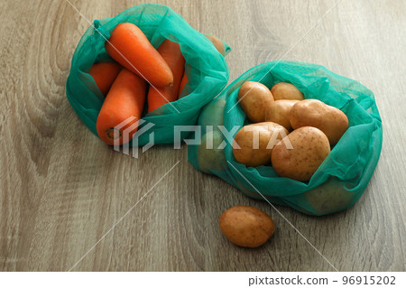 Net bags with vegetables on wooden table 96915202
