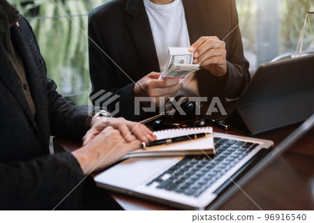 Businessman giving bribe money in the envelope to partner in a corruption scam in office. 96916540