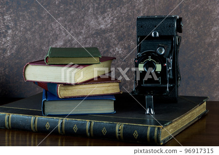 Old Books and Old Folding Camera on a Varnished Wooden Surface Old Books and Old Folding Camera on a Varnished Wooden Surface 96917315