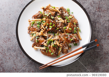 Japanese cuisine fried beef steak with beech mushrooms in teriyaki sauce with green onion and sesame close-up in a plate. Horizontal top view Japanese cuisine fried beef steak with beech mushrooms in teriyaki sauce with green onion and sesame close-up in a plate. Horizontal top view 96919080