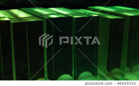 Solid glass blocks stand in a row in a dark room in green light Solid glass blocks stand in a row in a dark room in green light 96919358