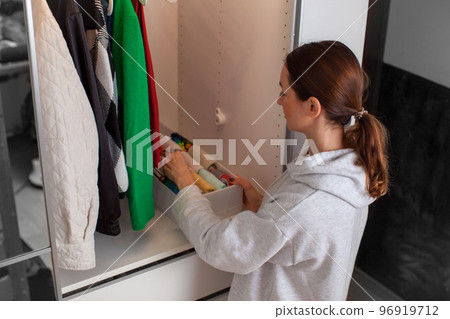 Caucasian young woman puts clothes in the closet. Magic of Tidying Up. 96919712