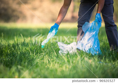 Man picking up plastic bottle, garbage collecting in forest cleaning planet, help garbage collection charity environment, garbage in the forest 96920327
