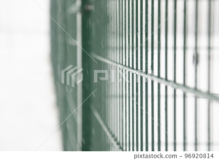 Background. Metal fence on the street in winter. Metal bars with frozen water 96920814