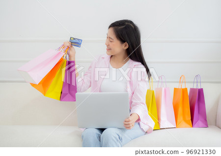 Young asian woman sitting on sofa using laptop computer shopping online with credit card. 96921330