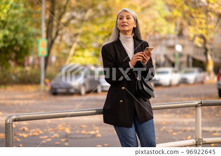 Long-haired woman in a black coat waiting for someone in the street 96922645