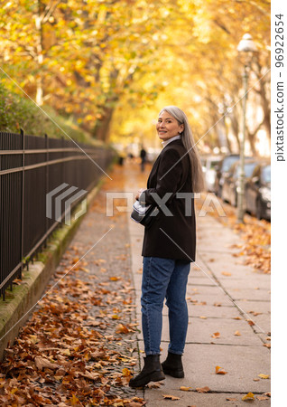 Long-haired good-looking mature woman in the street of autumn park Long-haired good-looking mature woman in the street of autumn park 96922654