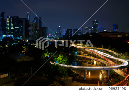 Night photo of a glowing multi-level road junction with heavy traffic. Roads in the metropolis Night photo of a glowing multi-level road junction with heavy traffic. Roads in the metropolis 96923498