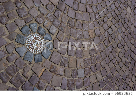 Old metal sewer hatch in the middle of the road, laid out of a smooth paving stone Old metal sewer hatch in the middle of the road, laid out of a smooth paving stone 96923685