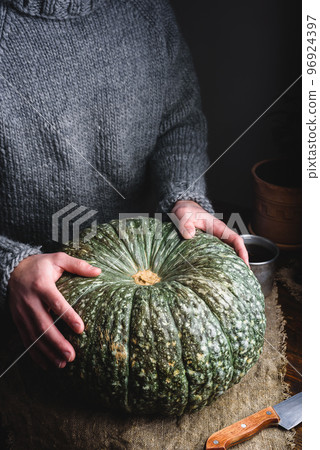 Hands Putting Ripe Green Pumpkin on Table 96924397