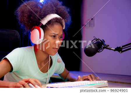 Young African American woman wearing headset play video game and live streaming online. 96924901