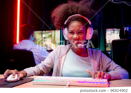 Young African American woman wearing headset play video game and live streaming online. 96924902