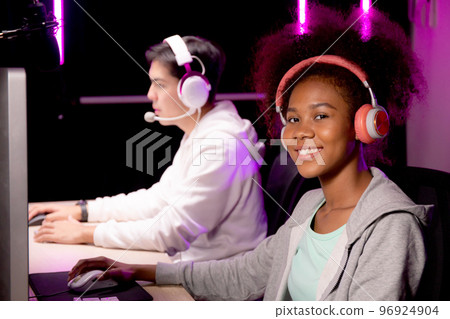 Young African American woman and asian man wearing headset play video game. 96924904