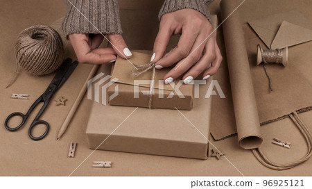 Woman packing Christmas gifts in brown paper 96925121