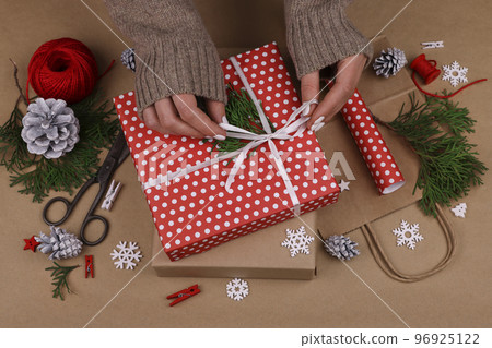 Woman packing Christmas gifts with red paper 96925122