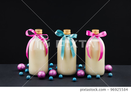 Homemade eggnog in bottles with pink and blue balls on dark background 96925584