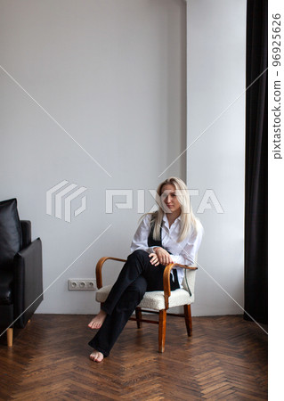 A young woman in a white shirt sits on a chair. A young woman in a white shirt sits on a chair. 96925626