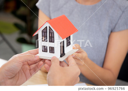 Closeup hands of young realtor man real estate giving house model to hands customer. Closeup hands of young realtor man real estate giving house model to hands customer. 96925766