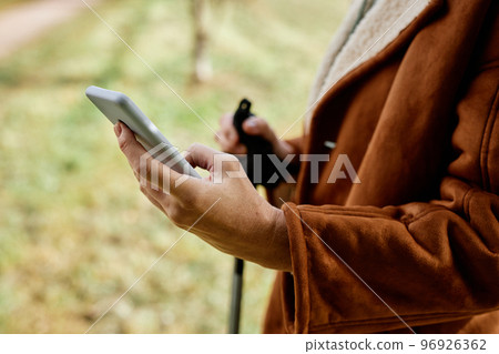 Closeup of woman holding smartphone at hike Closeup of woman holding smartphone at hike 96926362