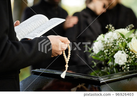 Close up of person in black praying at outdoor funeral 96926403