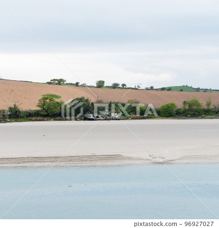 Sandy seashore. Calm water. The ship on the shore. A plowed field. 96927027