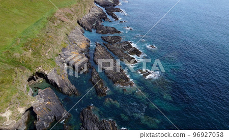 Rocky shores of the Celtic Sea along the route of the Wild Atlantic Way, top view. Seascape of the southern coast of Ireland. Beautiful rocky slopes. Aerial photo. Rocky shores of the Celtic Sea along the route of the Wild Atlantic Way, top view. Seascape of the southern coast of Ireland. Beautiful rocky slopes. Aerial photo. 96927058