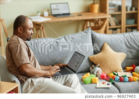 Single father working from home and using laptop 96927403