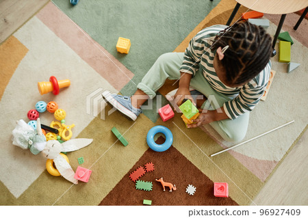 Toddler playing with colorful toys on carpet 96927409