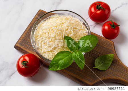 Bowl of grated parmesan and tomatoes over marble surface. Bowl of grated parmesan and tomatoes over marble surface. 96927531