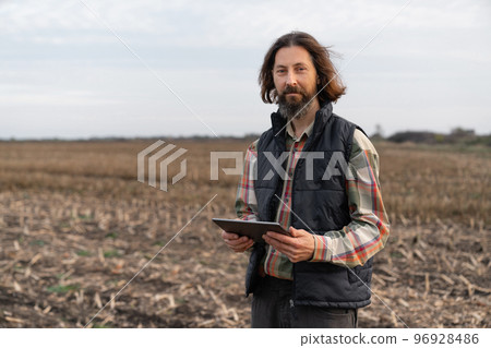 Farmer with digital tablet in young wheat field. Farmer with digital tablet in young wheat field. 96928486
